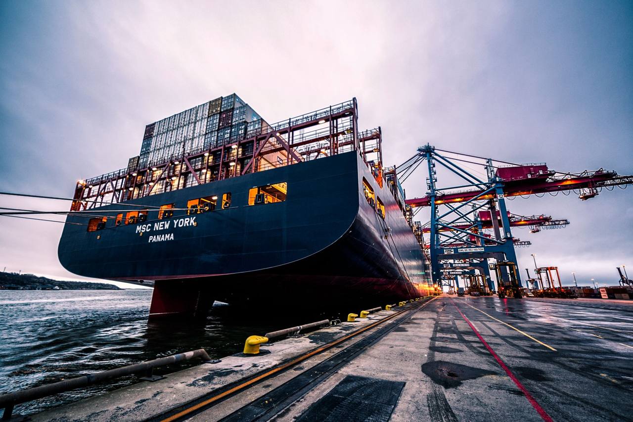 Large container ship docked under port cranes